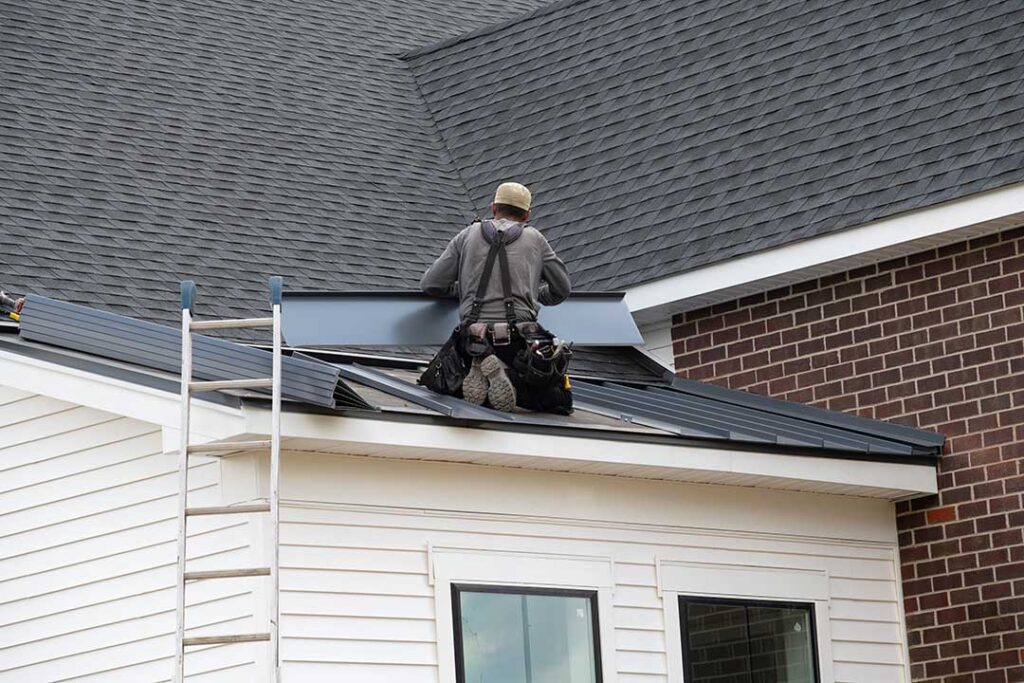 Person examining bruised roof shingles and granules collected in a gutter after a hailstorm.