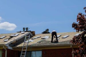 Roof shingles lifted by wind with water stains visible on attic roof decking
