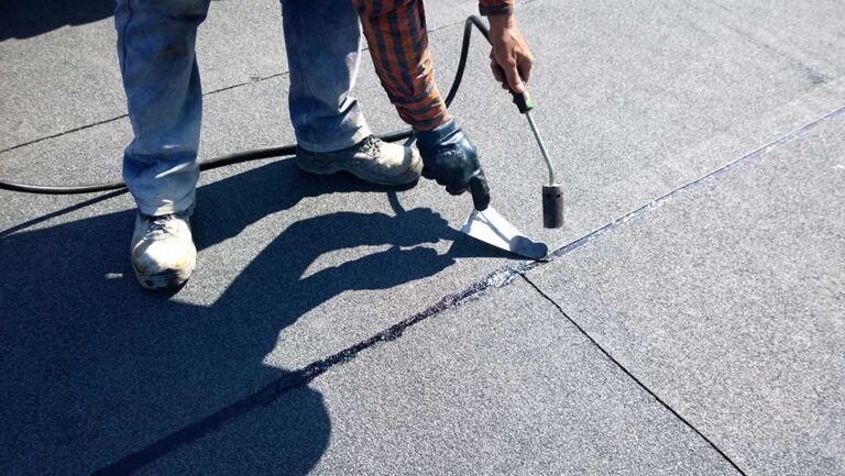 Metal flashing protects the joint between shingles and a chimney on a residential roof.